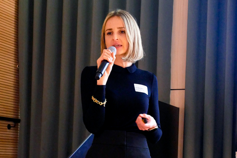 Christina Mayr steht auf der Bühne und spricht in ein Handmikrofon.