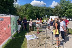 Eine Gruppe von Menschen schauen auf einen Plan und Plakate, über die eine Person referiert