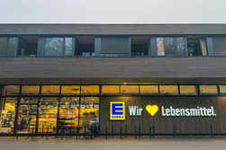 EDEKA Supermarkt unten mit Wohnungen oben, außen Holzfassade