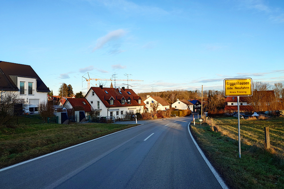 Straße zwischen Häusern und Wiesen mit Ortsschild Giggenhausen